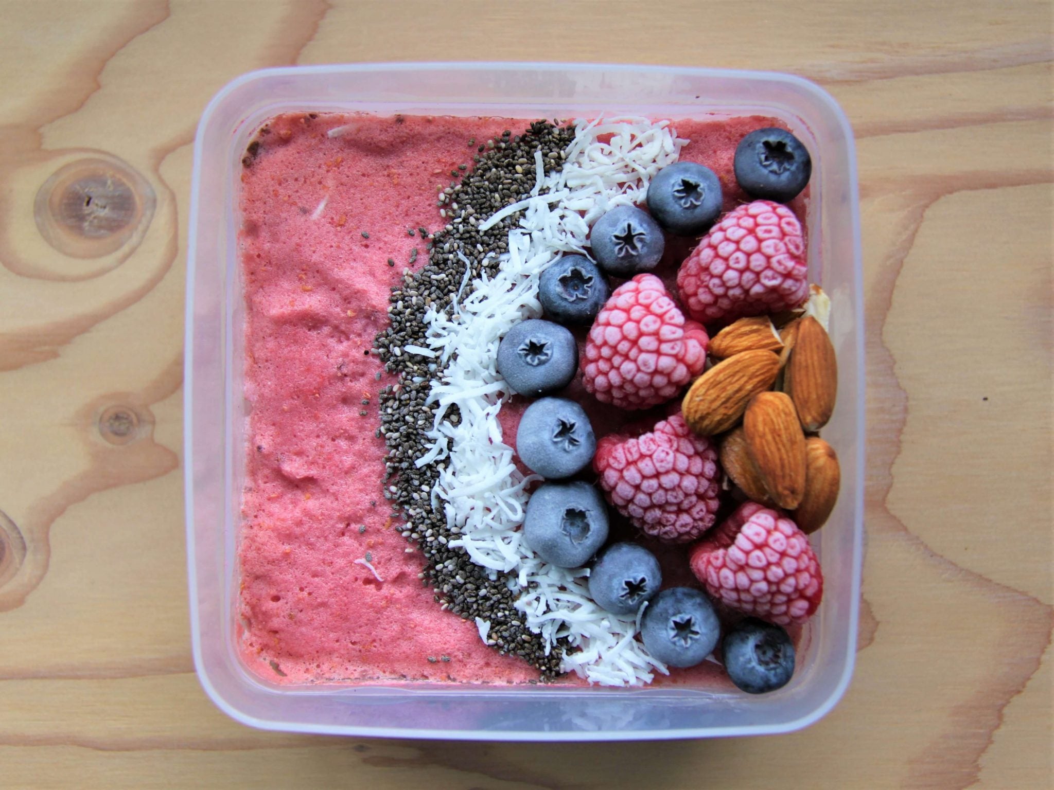 Pink smothie bowl with nuts and berries on top