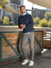 Man standing and leaning against an outdoor counter while wearing a navy blue men's fitted sweater.