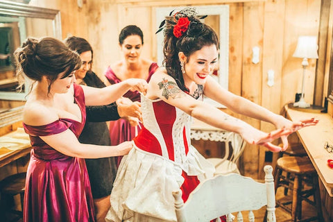 Julia being laced into her Gallery Serpentine Turn of the Century corset by her bridesmaids