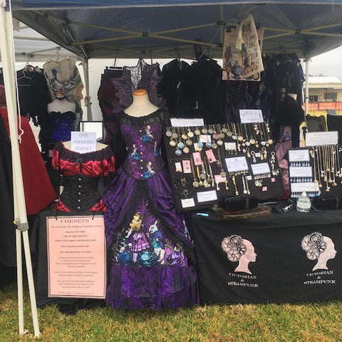 dark purple Alice in Wonderland corset gown beside an Australian made black corset on a manneqin at market stall