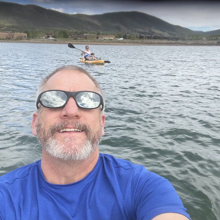 Uomo che pagaia sul Dillon Reservoir con la montagna sullo sfondo