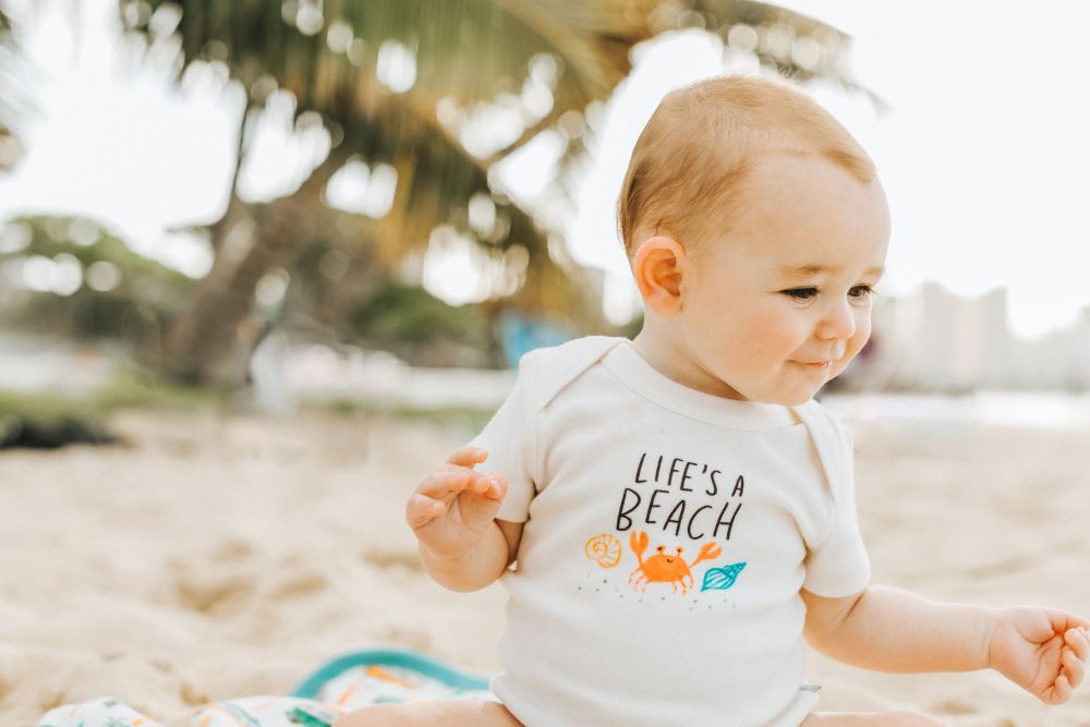 baby on beach wearing finn + emma bodysuit