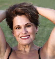 mature woman with brunette hair. Arms behind her head and smiling | Parisians Pure Indulgence