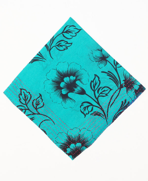 Bold and bright teal cotton bandana that has black patterns contrasting the bright style