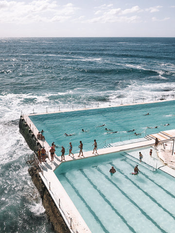 A view of Bondi Beach in Australia with a group of people swimming in the Bondi Icebergs pool