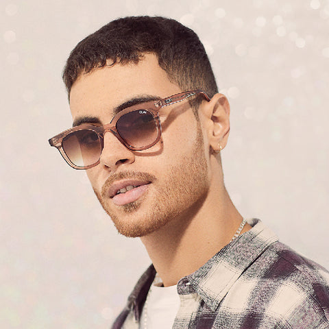 A male model posing wearing a black and brown plaid shirt with QUAY SIDE NOTE brown sunglasses