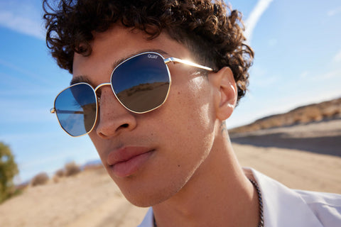 man wearing QUAY BIG TIME sunglasses standing on a desert road