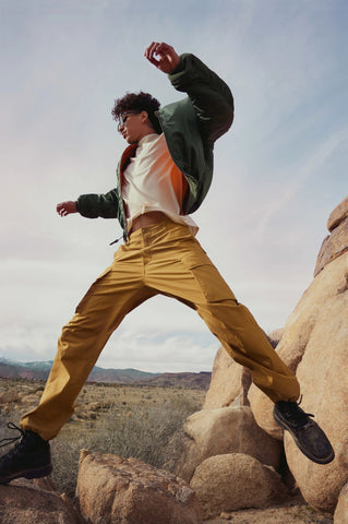 Man jumping across two boulders wearing QUAY sunglasses