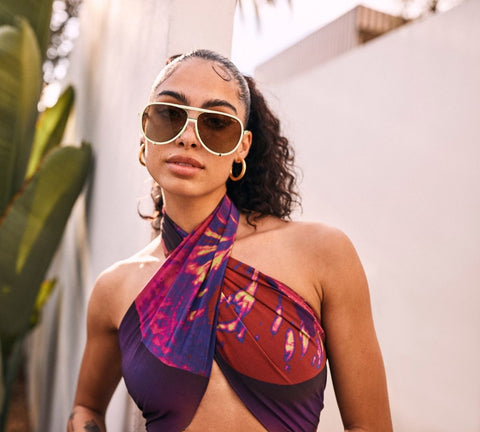 A female model posing wearing a purple scarf top with QUAY HIGH PROFILE white sunglasses