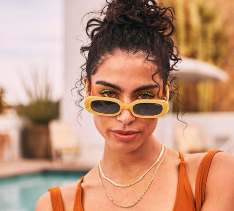 A female model posing poolside wearing QUAY SO SERIOUS yellow sunnies