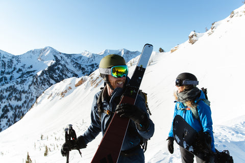Two people backcountry skiing and snowboarding while wearing Wildhorn ski helmets that are compulsory