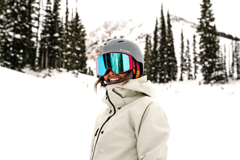 A person smiling at the camera in their snow gear and Wildhorn helmet