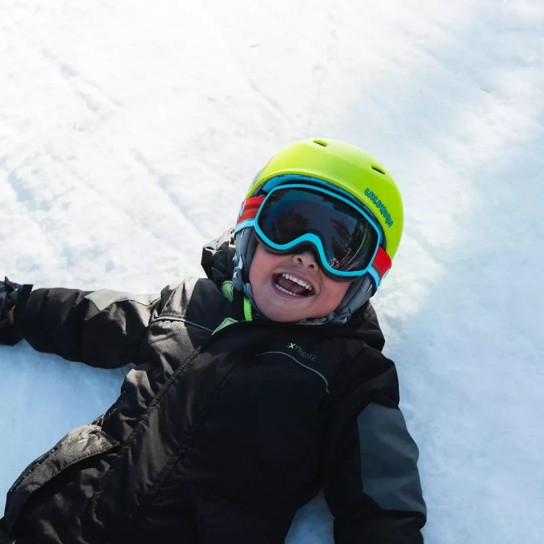 kid laughing in the snow wearing a spire helmet and goggle combo