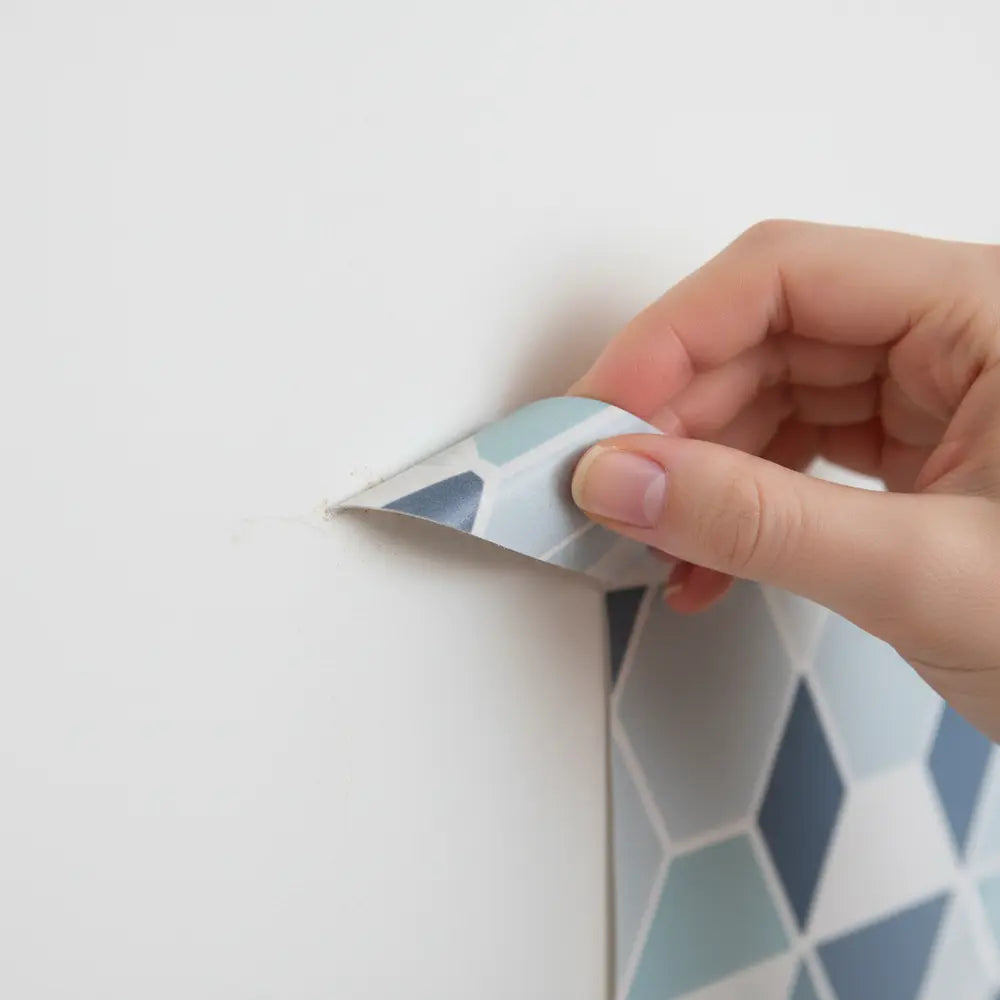 Peel and stick tile being removed from wall cleanly.