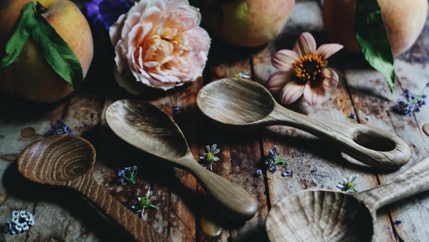 Handgjorda träskedar tillsammans med lantliga element och blommor