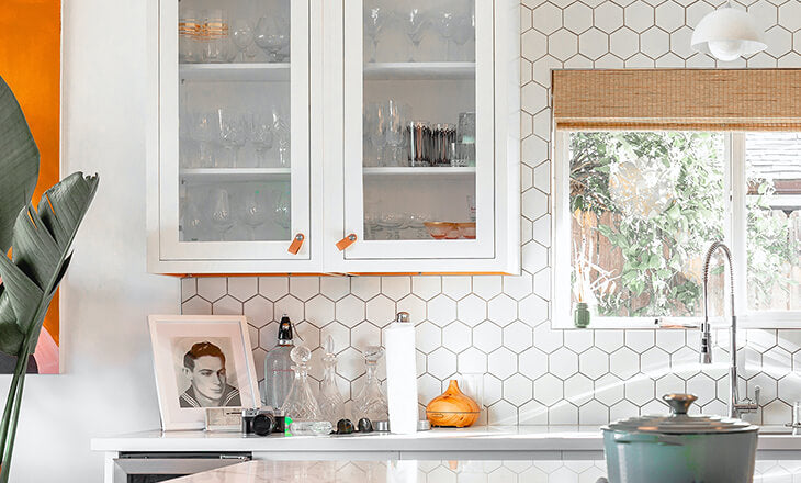 A close-up of the kitchen photo compressed with TinyPNG at 1x scale, centering on a cabinet and background tiles, with various accessories on the counter. The grout lines show the pixelation.