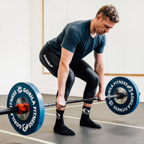 A person doing a deadlift with a barbell. Deadlifts are also essential for strengthening knees, but should not be the first exercise sore knees are exposed to.