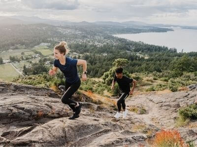 Two joggers going up a cliff with a lake behind them. They're wearing Bracelayer compression tights for injury free exercise, compression gear, compression for injury, compression for recovery