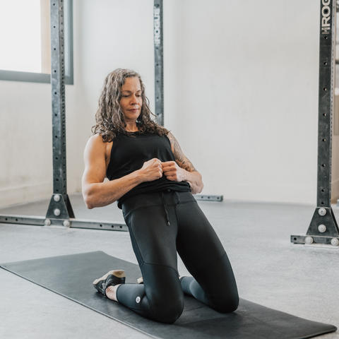 A woman performing a reverse nordic curl, am extremely challenging knee strengthening exercise for the quadriceps which involves leaning backwards from a kneeling position.