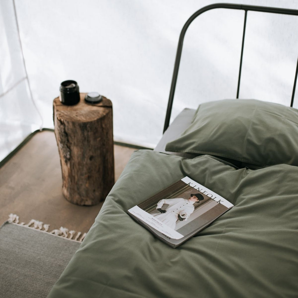 Inside of tent with metal bed and dark green covers for best camping essential tips