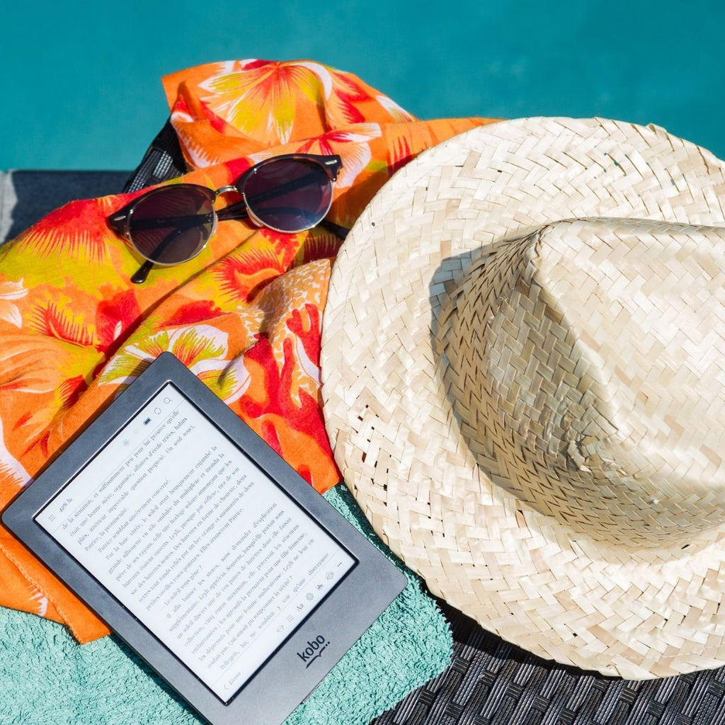 Kindle book, straw sun hat, sunglasses and orange cover up for staycation essentials