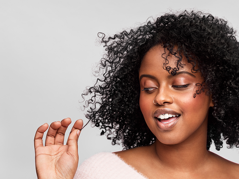 Woman with dark curly hair plays with a single strand