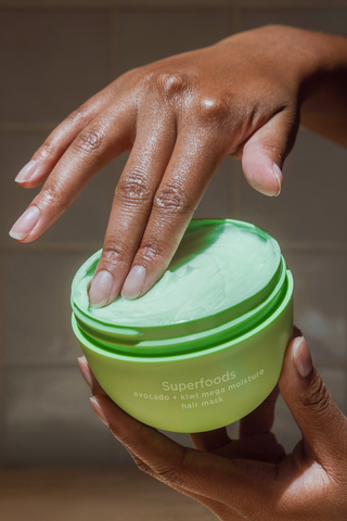 Fingers dipping into a green Avocago Mega Moisture Mask