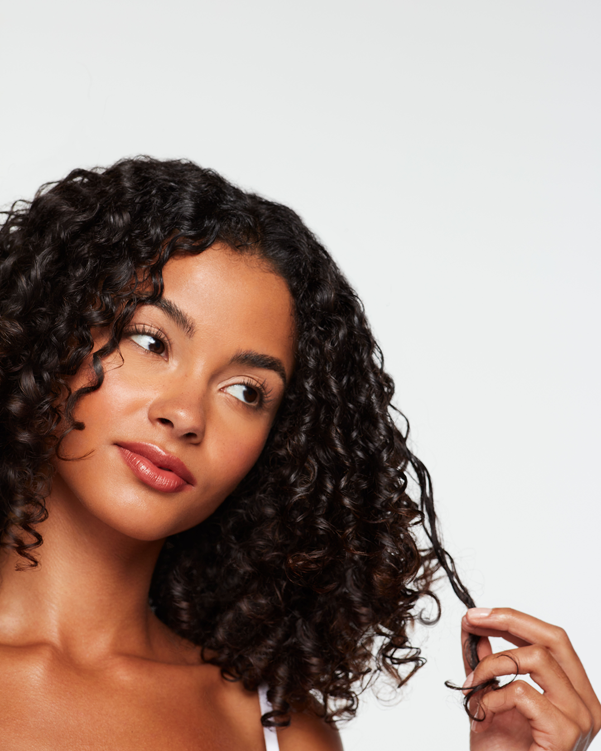 Woman with dark curly hair twirls a strand around her finger