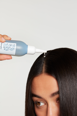 woman with dark hair applying oil to her partline