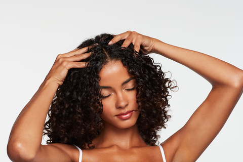 woman with dark curly hair massaging her scalp