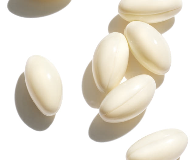 Six vitamin capsules on a white background. 