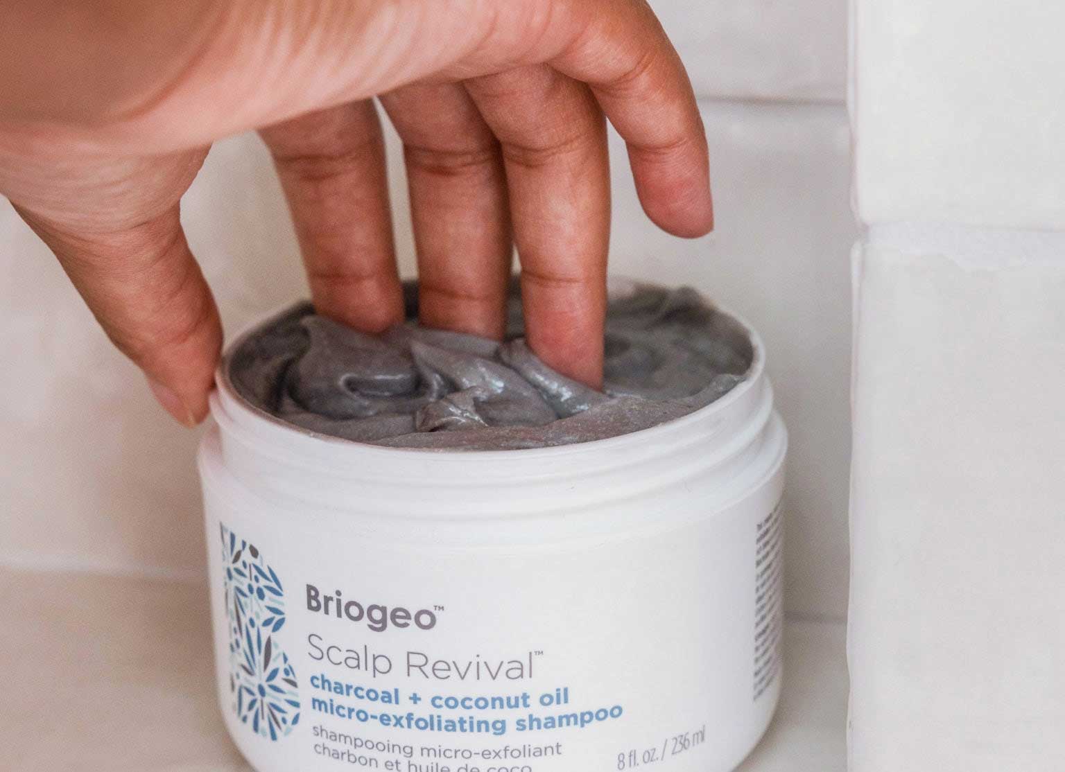 Hand dipping Scalp Revival micro-exfoliating shampoo in shower. 