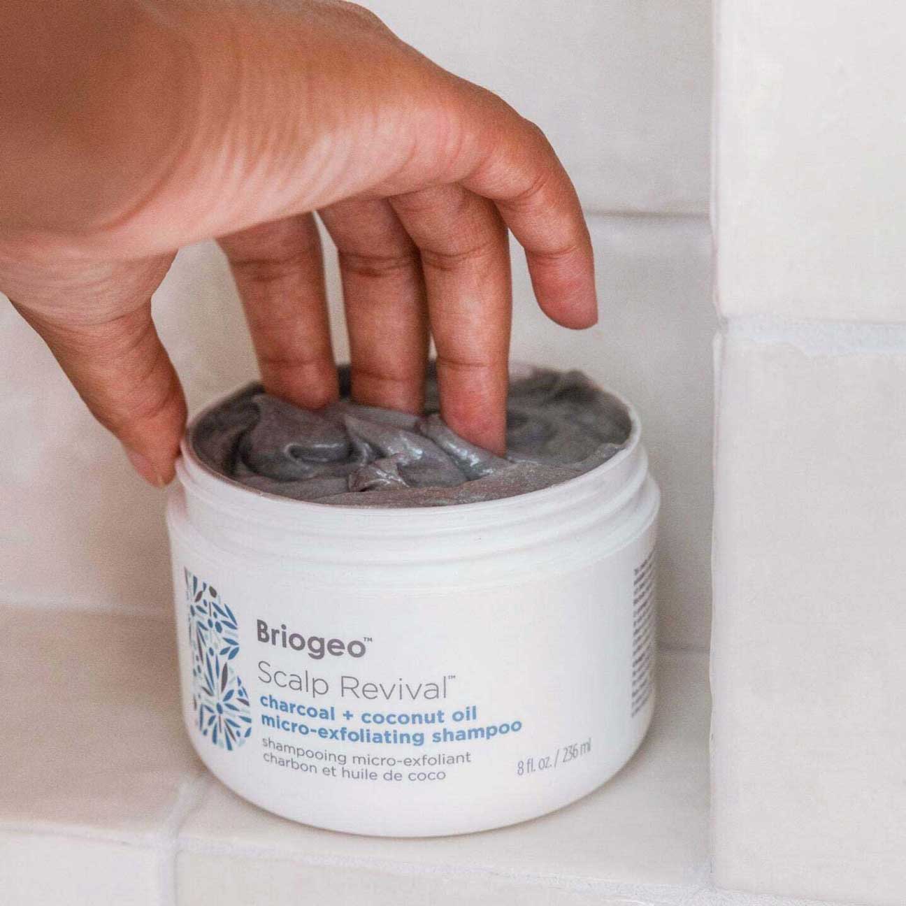 Hand dipping Scalp Revival micro-exfoliating shampoo in shower. 