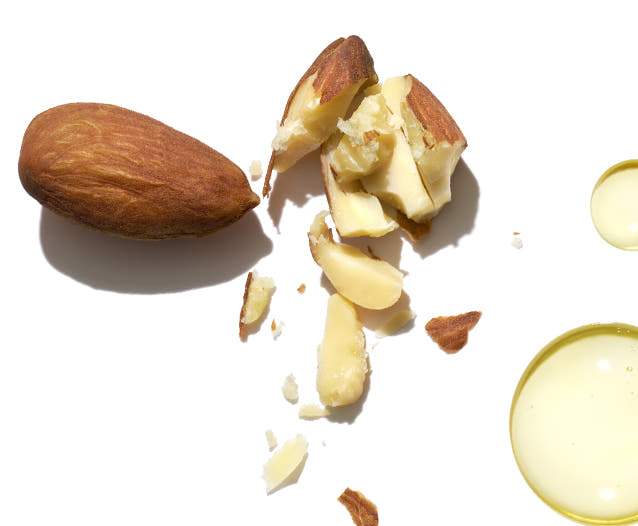 Crushed almonds beside yellow oil drop on a white background. 