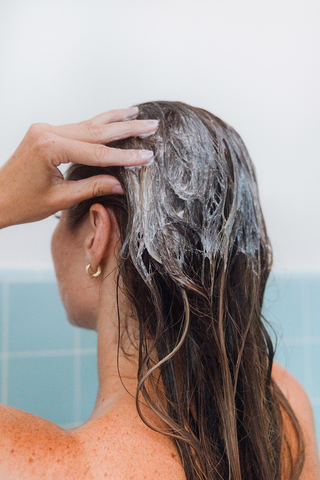 Woman with brown hair shampooing her scalp
