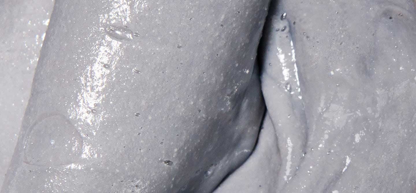 Grey, gritty texture shot of scalp revival exfoliating shampoo.