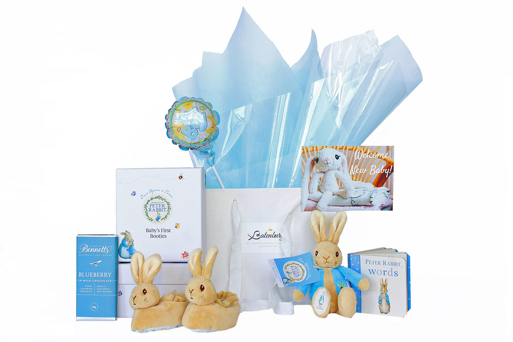 Gift bag with blue Vilene Peter Rabbit themed gift hamper with soft toy, baby boots, baby book and chocolate.