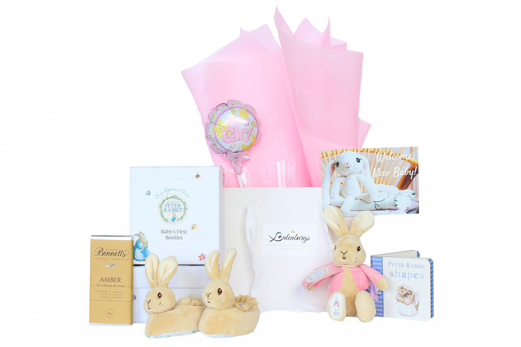 White gift bag with pink Vilene, Peter Rabbit boots, Flopsy Bunny soft toy, Peter rabbit book, It's a girl balloon mini and Bennett's of Mangawhai chocolate