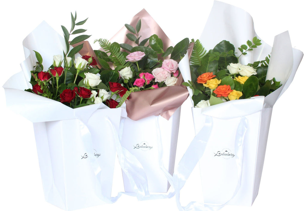 Three white gift bags with selection of different coloured roses including red, white, pink, orange and yellow. Delivered within Auckland city by Batenburgs Gift Hampers