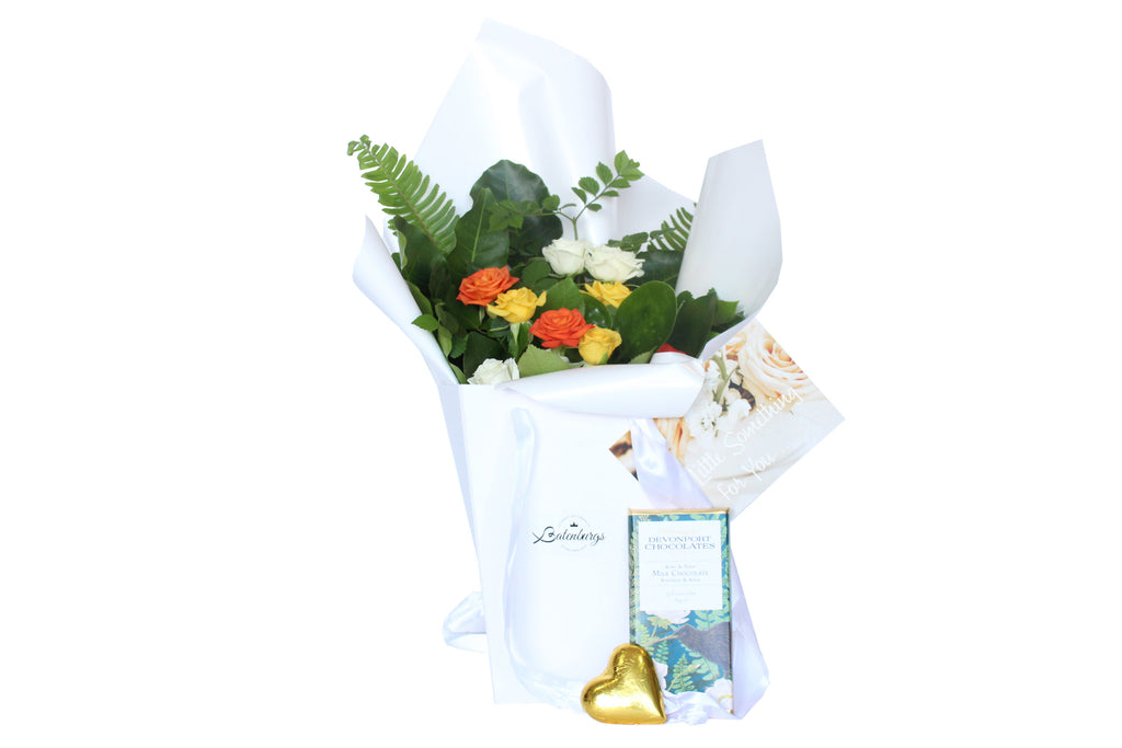 Orange, yellow and white roses packed in a deluxe white gift bag with Dovonport Chocolate bar and a chocolate heart