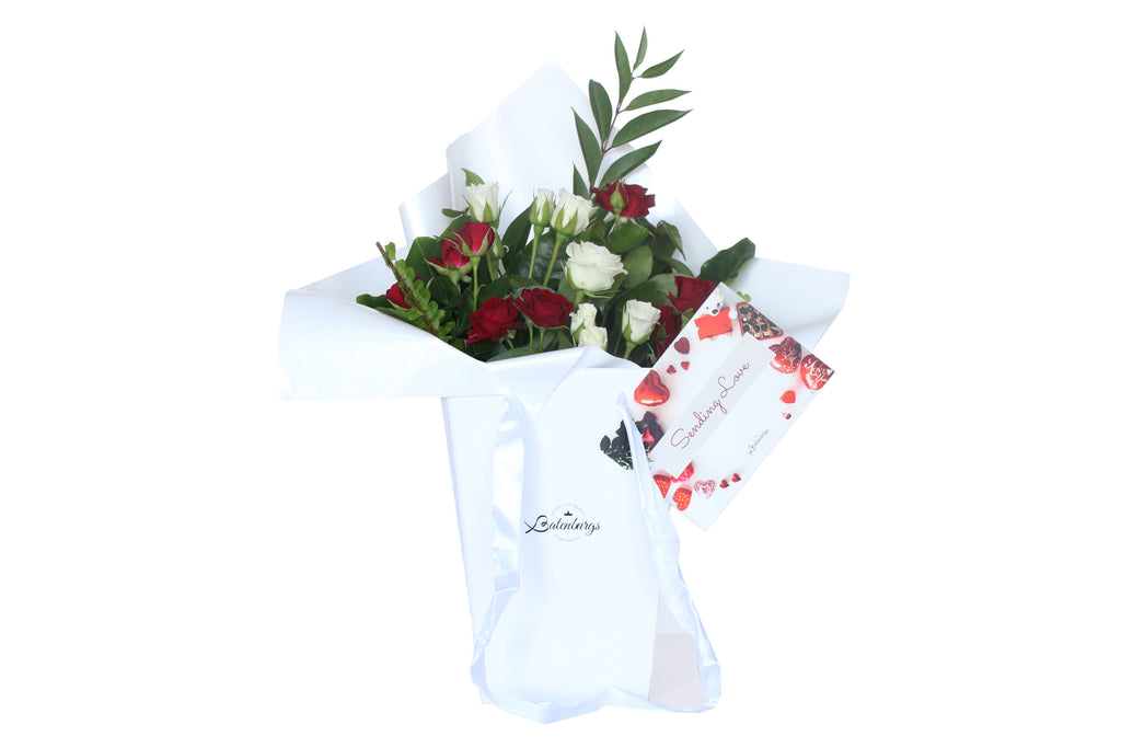 Red and white roses packed in a deluxe white gift bag with card message