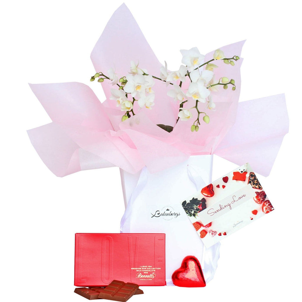 White orchid flower in a deluxe white gift bag with I love you chocolate and a chocolate heart. From Batenburg's Gift Hampers