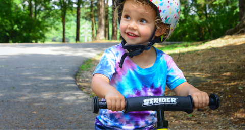 bild eines lächelnden Jungen, der sich mit Helm an seinem Fahrrad festhält.