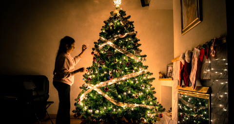 girl in living room standing next to a Christmas tree