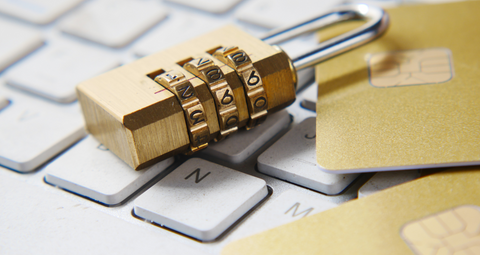 Internet Safety. A gold code padlock lay on top of a computer keyboard with bank cards.