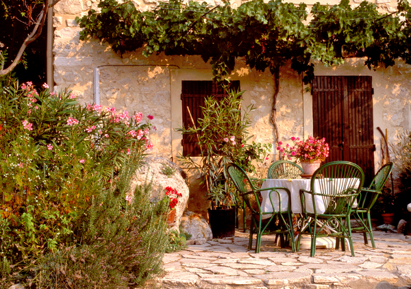 French Provincial garden aesthetic with flowers, cobbled streets, and chairs and a table.