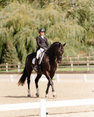 Dressage Rider Wearing White Riding Pants on Horse in Front of Trees in Background