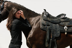 Western Style Horse Rider Wearing Black Riding Pants Standing Next to Brown Horse