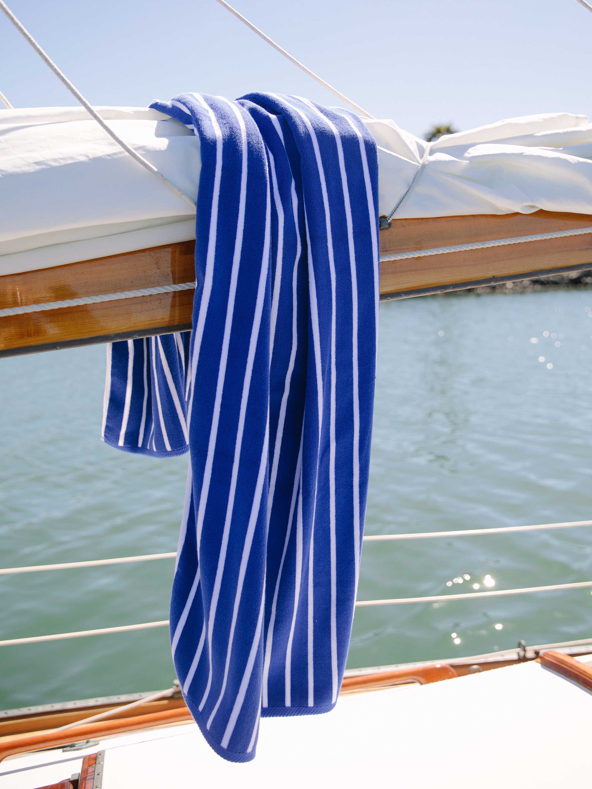 A royal blue striped Cabana Towel draped on the side of a boat.