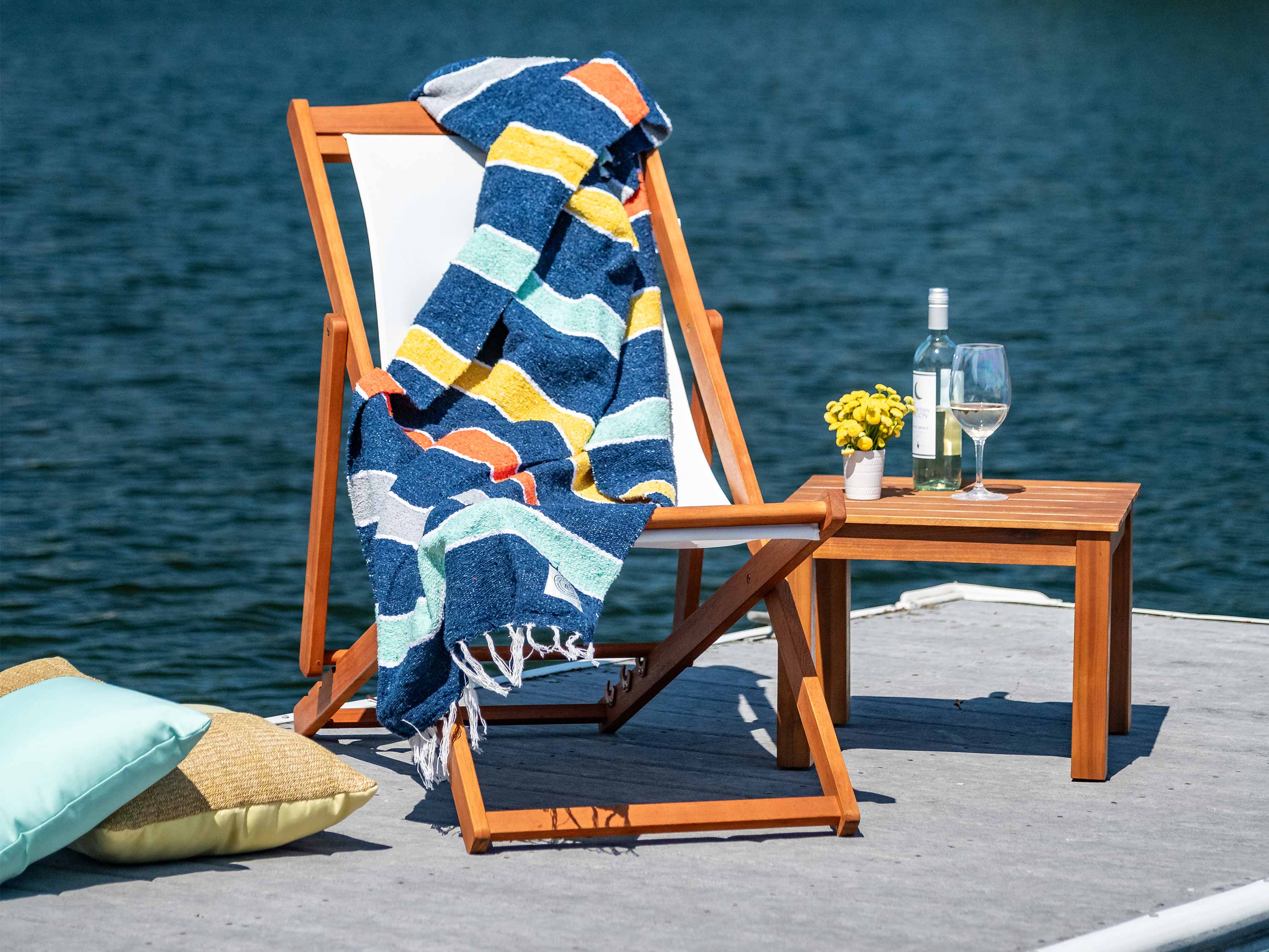 A striped Mexican Blanket draped over a chair by a waterfront.